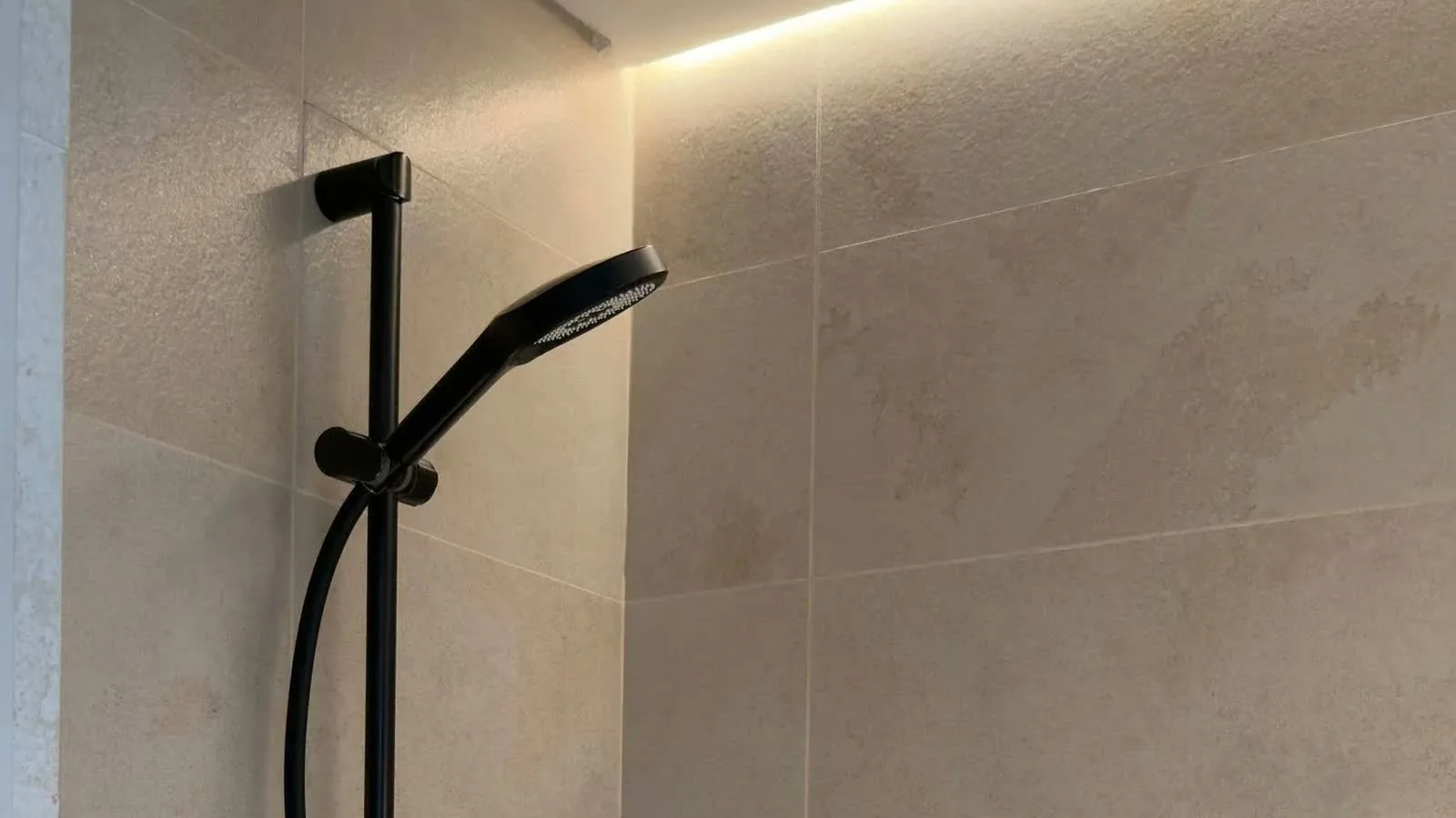 Bodengleiche Dusche mit warmem Travertin und schwarzen Armaturen