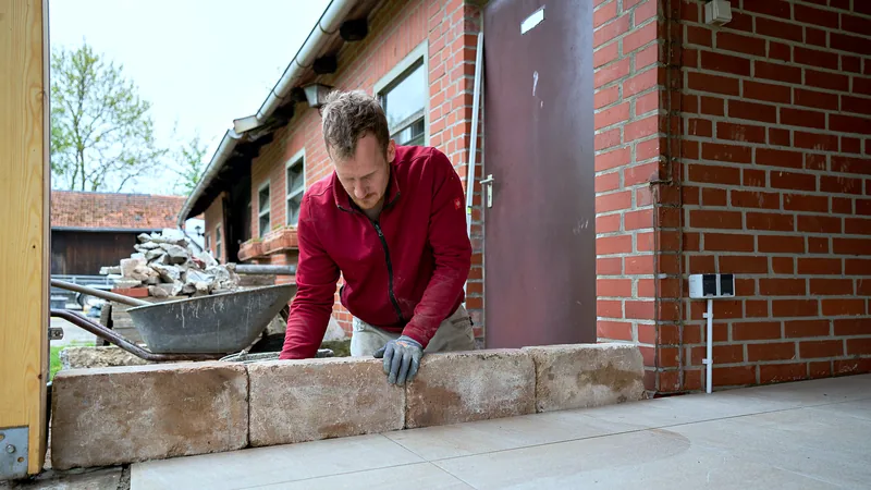 Sandsteinquader wird von Hand auf die Mauer gesetzt