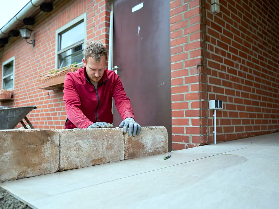 Setzen einer Randeinfassung aus Sandstein neben der fertigen Fläche