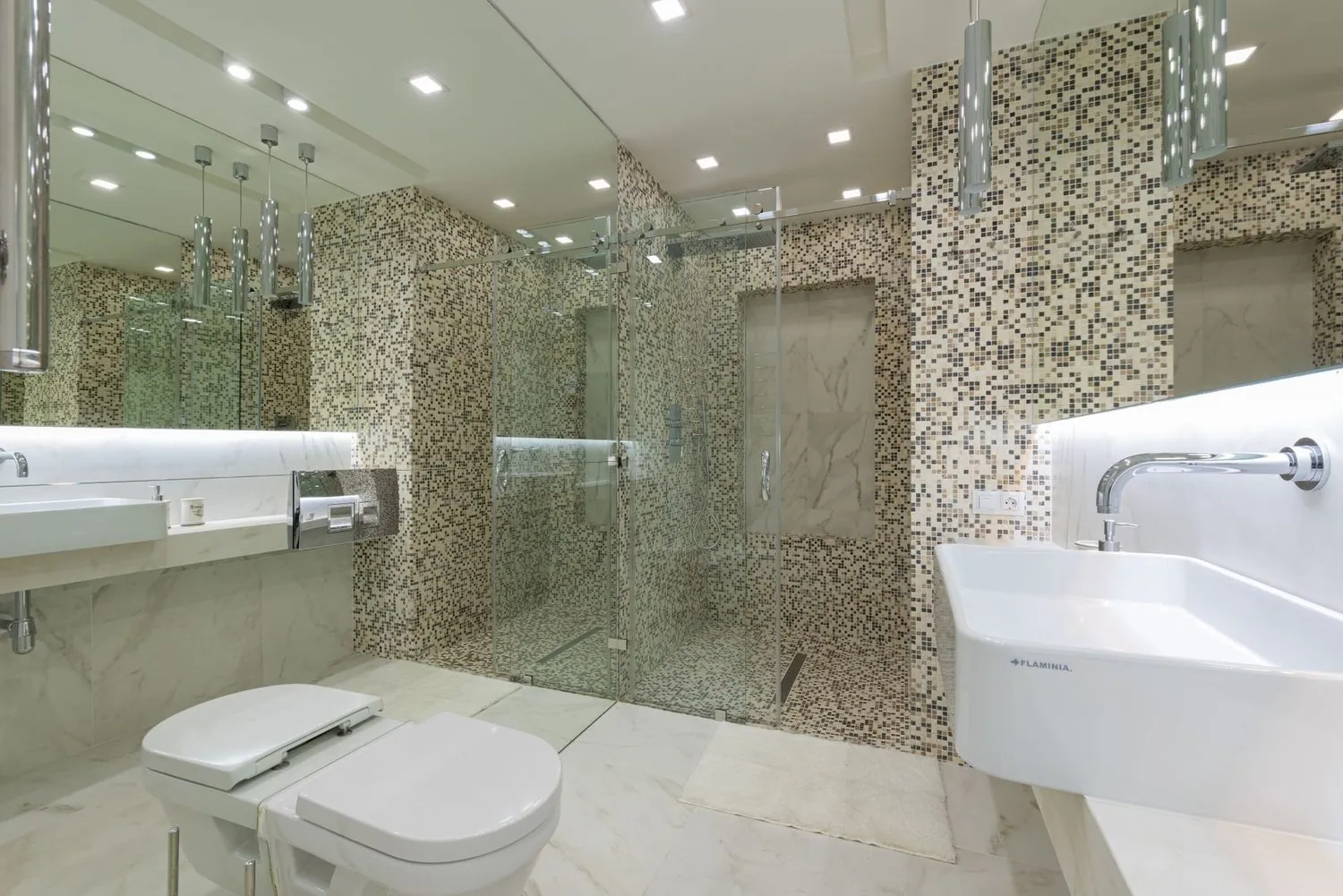Bad mit Mosaikfläche neben einer Glasdusche